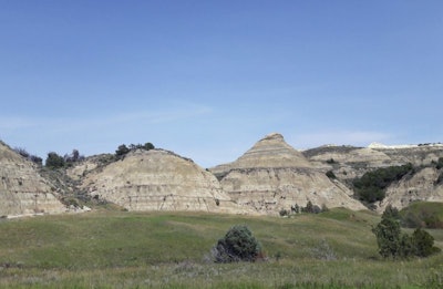 This Aug. 1, 2018, file photo, shows a view of the badlands landscape at Theodore Roosevelt National Park near Medora, N.D. Environmental groups opposing the site of an oil refinery being developed near Theodore Roosevelt National Park in North Dakota want a judge to reconsider his recent recommendation that state regulators dismiss the groups' challenge. They accuse the Davis Refinery developer of not updating state officials about revisions to the project. Meridian Energy Group says it had no reason or requirement to do so. (AP Photo/Steve Karnowski)