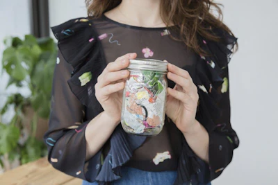 This undated photo provided by Man Repeller shows Lauren Singer in New York holding her mason jar containing one years worth of waste she produced. Once an industrial term, Zero Waste has become a rallying cry for a small but influential number of households trying to winnow their annual trash to, well, zero. From California to Canada to Brooklyn and beyond, a small but growing number of households are joining together in what has become what seems to be a movement, declaring that less may be more, but zero is the best of all, at least where contributing to landfills is concerned. (Bridget Badore/Man Repeller via AP)