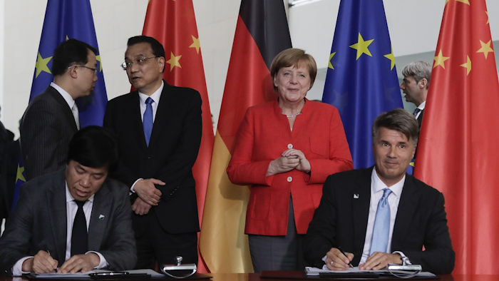 In this July 9, 2018 file photo German Chancellor Angela Merkel, second from right, and Chinese Premier Li Keqiang, third from left, attend a contracts signing ceremony between German car maker BMW CEO Harald Krueger, right, and Qi Yumin CEO of the Brilliance Group, left front, during a meeting in the chancellery in Berlin. Image credit: AP Photo/Markus Schreiber, file