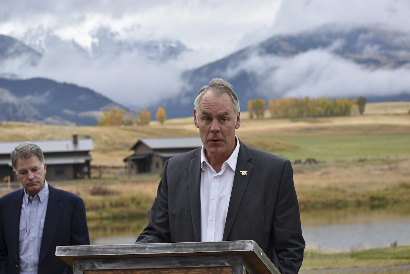 In this Oct. 8, 2018 photo, U.S. Interior Secretary Ryan Zinke announces a ban on mining claims north of Yellowstone National Park as K.C. Walsh, left, president of Simms Fishing Products, listens near Emigrant, Mont. The Trump administration is considering using West Coast military bases or other federal properties as transit points for shipments of U.S. coal and natural gas to Asia. (AP Photo/Matthew Brown)