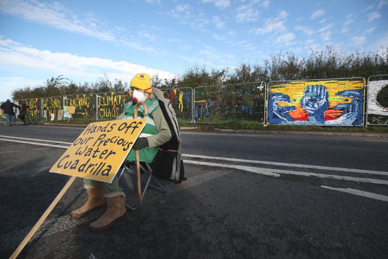 A fracking protester sits outside energy firm Cuadrilla's site in Preston New Road, Little Plumpton, in Lancashire, England, Monday, Oct. 15, 2018. The protesters have said their fight has just 'got serious' as the controversial process is due to get underway in Lancashire. Police closed off the road on Monday morning as about 50 protesters gathered outside the site ahead of the start of the hydraulic fracturing process. (Peter Byrne/PA via AP)