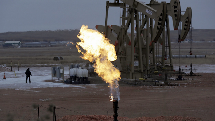 In this Oct. 22, 2015, file photo, workers tend to oil pump jacks behind a natural gas flare near Watford City, N.D. Image credit: AP photo/Eric Gay, File