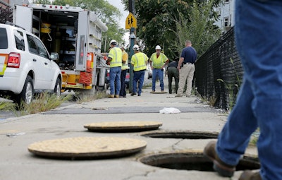 A worker with Columbia gas stands over an open man hole as the crew works to make sure there are no gas leaks at the corner of Parker and Salem Streets in Lawrence, Mass., Friday, Sept. 14, 2018. Multiple houses were damaged from gas explosions and fires triggered by a problem with a gas line that feeds homes in several communities north of Boston. (AP Photo/Mary Schwalm)