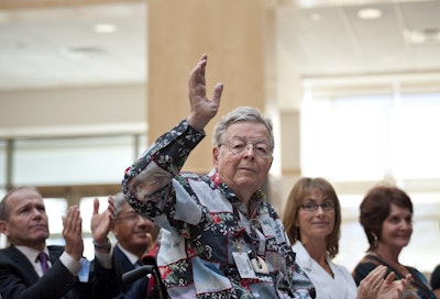 In this undated photo, Medtronic founder Earl Bakken waves as he's acknowledged by new CEO Omar Ishrak at the annual shareholders meeting at Medtronic's Fridley, Minn., headquarters. Image credit: Glen Stubbe/Star Tribune via AP