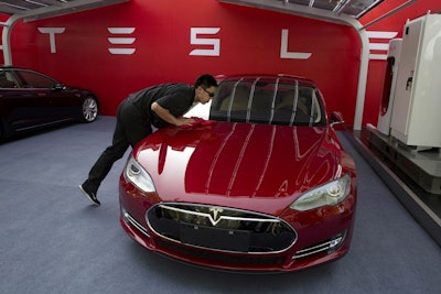 In this April 22, 2014, file photo, a worker cleans a Tesla Model S sedan before an event to deliver the first set of cars to customers in Beijing. Image credit: AP Photo/Ng Han Guan, File