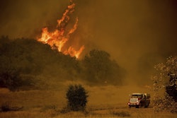 In this Dec. 9, 2017 file photo, a fire engine passes flames as a wildfire burns along Santa Ana Road near Ventura, Calif. Image credit: AP Photo/Noah Berge, File