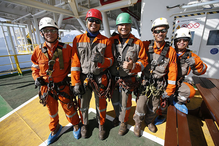 In this photo taken on Tuesday, Oct. 30, 2018, workers pose for a photo on Turkey's new drillship 'Conquerer' off the coast of Antalya, southern Turkey. Turkey says it has begun a search for oil and gas in east Mediterranean waters in a move that could stoke regional tensions. The drillship ‘Conquerer’ began exploratory drilling Wednesday off Antalya on Turkey’s southern coast. (AP Photo/Lefteris Pitarakis)
