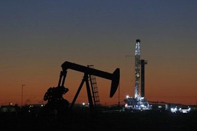 In this Oct. 9, 2018, file photo, an oil rig and pump jack work along the roadside of FM 1788 in Midland, Texas. With more barrels of oil being pumped monthly from the Permian Basin, New Mexico is among the nation's top producing states.(Jacob Ford/Odessa American via AP)
