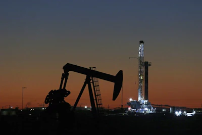 In this Oct. 9, 2018, file photo, an oil rig and pump jack work along the roadside of FM 1788 in Midland, Texas. With more barrels of oil being pumped monthly from the Permian Basin, New Mexico is among the nation's top producing states.(Jacob Ford/Odessa American via AP)