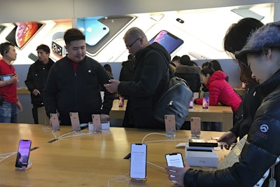 People buy latest iPhone while others try out its latest model at an Apple Store in Beijing, Tuesday, Dec. 11, 2018. Image credit: AP Photo/Andy Wong
