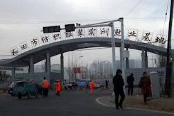 In this Wednesday, Dec. 5, 2018, photo, residents past by the entrance to the 'Hotan City apparel employment training base' where Hetian Taida has a factory in Hotan in western China's Xinjiang region. Image credit: AP Photo/Ng Han Guan
