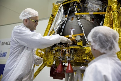 SpaceIL co-founder Yonatan Winetraub, left, inserts a time capsule into the SpaceIL lunar module, an unmanned spacecraft, that is on display in a special 'clean room' where the space craft is being developed, during a press tour of their facility near Tel Aviv, Israel, Monday, Dec. 17, 2018. Image credit: AP Photo/Ariel Schalit