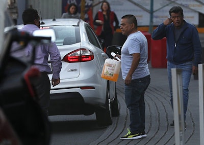 A man walks with a container of gasoline in Mexico, City, Tuesday, Jan. 8, 2019. Motorists are lined up for a fourth straight day at gas stations in parts of Mexico as the government continues to restrict pipeline deliveries to combat illegal fuel taps. (AP Photo/Marco Ugarte)