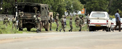 Zimbabwean soldiers are situated where police are clashing with protestors over fuel hikes in Harare, Zimbabwe, Monday, Jan. 14, 2019. Zimbabwean police on Monday fired tear gas in suburbs of the capital an attempt to disperse angry demonstrators who burned tires and threw stones to protest fuel price hikes. (AP Photo/Tsvangirayi Mukwazhi)