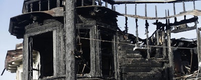 A charred utility pole and building are shown at the scene of a Wednesday fire on Geary Boulevard in San Francisco, Thursday, Feb. 7, 2019. A gas explosion shot a tower of flames into the sky and burned five buildings including one of the city's popular restaurants before firefighters brought the blaze under control. (AP Photo/Jeff Chiu)