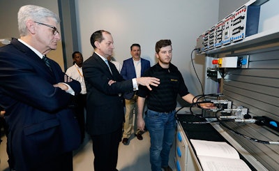U.S. Secretary of Labor Alexander Acosta, center, asks about the hydraulic maintenance and troubling shooting simulator with a student, while Mississippi Gov. Phil Bryant, left, listens, at the Continental Tire manufacturing plant, Friday, Feb. 8, 2019, in Clinton, Miss., during a tour of the Continental Tire Training Center. (AP Photo/Rogelio V. Solis)