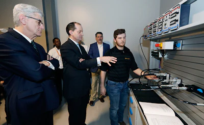 U.S. Secretary of Labor Alexander Acosta, center, asks about the hydraulic maintenance and troubling shooting simulator with a student, while Mississippi Gov. Phil Bryant, left, listens, at the Continental Tire manufacturing plant, Friday, Feb. 8, 2019, in Clinton, Miss., during a tour of the Continental Tire Training Center. (AP Photo/Rogelio V. Solis)