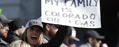Audrey Carlson of Denver waves a placard during a rally outside the State Capitol Tuesday, March 5, 2019 in opposition of lawmakers' plan to advance a bill to overhaul the state's oil and gas regulations. (AP Photo/David Zalubowski)