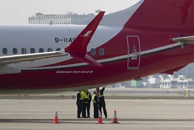 Ground crew chat near a Boeing 737 MAX 8 plane operated by Shanghai Airlines parked on tarmac at Hongqiao airport in Shanghai, China, Tuesday, March 12, 2019. Image credit: AP Photo