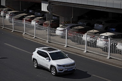 An SUV moves past dust-covered new Toyota cars stored underneath an overpass in Beijing, Thursday, March 14, 2019. Image credit: AP Photo/Andy Wong