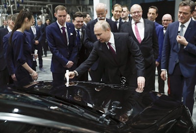 Russian President Vladimir Putin signs a car hood during an opening ceremony of the Mercedes Benz automobile assembly plant outside Moscow, Russia, Wednesday, April 3, 2019, with Chairman of the Board of Management of Daimler AG Dieter Zetsche, background centre left, and German economics ministers Peter Altmaier, centre right. Image credit: AP Photo/Pavel Golovkin, Pool