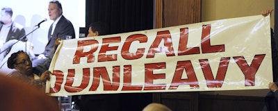 Protesters unfurl a banner as Gov. Mike Dunleavy speaks during a roadshow with Americans for Prosperity in 49th State Brewing Company on Tuesday, March 26, 2019. (Bill Roth/Anchorage Daily News via AP)
