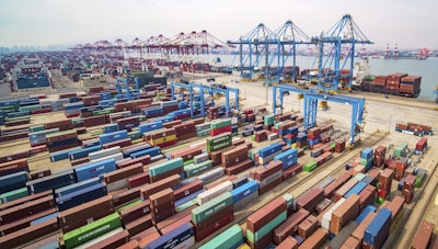In this March 8, 2019, photo, trucks move at a container port in Qingdao in eastern China's Shandong Province. Image credit: Chinatopix via AP