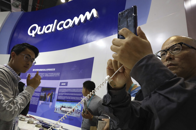 In this Nov. 6, 2018 file photo, attendees look at the latest technology from Qualcomm at the China International Import Expo in Shanghai. Image credit: AP Photo/Ng Han Guan, File