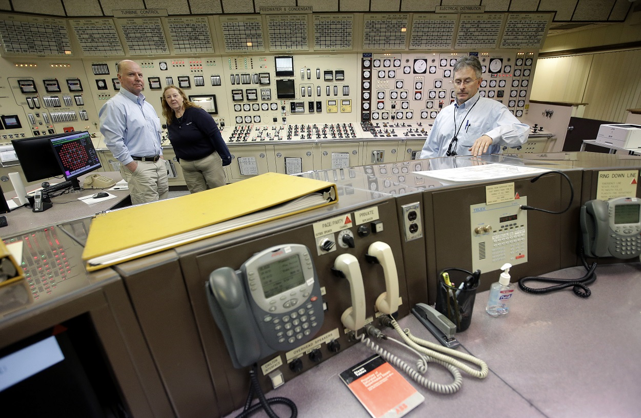 Control Room Supervisor Bob Sheridan, of Duxbury, Mass., left, and Senior Reactor Operator Kelly Connerton, of Middleborough, Mass., center, stand together in the Control Room Simulator moments before a simulated reactor shutdown, Tuesday, May 28, 2019, at a training facility several miles from the Pilgrim Nuclear Power Station, in Plymouth, Mass. Image credit: AP Photo/Steven Senne
