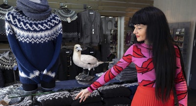 In this photo taken on Friday, 3 May, 2019, sales assistant Nuria Medina Marin gestures to a 'lopi' sweater in the Nordic store in Reykjavik. Image credit: AP Photo/Egill Bjarnason