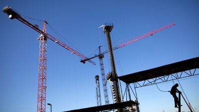 In this Oct. 23 file photo, a worker climbs a ladder as cranes work the construction site for the new corporate headquarters of Norfolk Southern Railway in Atlanta.