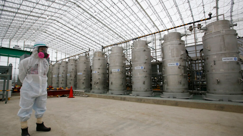 In this Nov. 12, 2014, file photo, a Tokyo Electric Power Co. (TEPCO) official wearing a radioactive protective gear stands in front of Advanced Liquid Processing Systems during a press tour at the Fukushima Dai-ichi nuclear power plant in Okuma, Fukushima Prefecture, northeastern Japan. Japan's economy and industry ministry has proposed gradually releasing or allowing to evaporate massive amounts of treated but still radioactive water at the tsunami-wrecked Fukushima nuclear plant. The proposal made Monday, Dec. 23, 2019, to a body of experts is the first time the ministry has narrowed down the options available to just releasing the water.