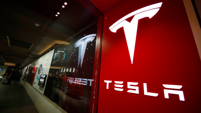 In this Saturday, Feb. 9, 2019, file photograph, a sign bearing the company logo stands outside a Tesla store in Cherry Creek Mall in Denver. Federal investigators have found that a 2018 crash and fire in Florida that killed the teenage driver of a Tesla Model S and a passenger was due to the car traveling at over 100 miles per hour on a curve. The National Transportation Safety Board says in a report released Thursday, Dec. 19, 2019 that the battery-powered car erupted in flames after colliding with a wall. The two 18-year-olds were trapped in the car.