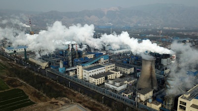 In this Nov. 28, 2019 photo, smoke and steam rise from a coal processing plant that produces carbon black, an ingredient in steel manufacturing, in Hejin in central China's Shanxi Province.