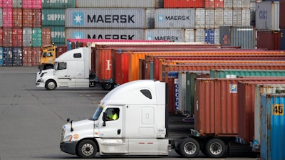 In this Oct. 2, 2019 file photo, trucks are positioned to haul shipping containers at a terminal where containers are stacked five-high on Harbor Island in Seattle.