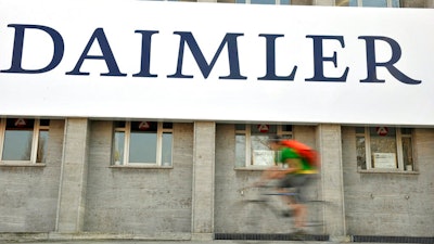 In this April 8, 2009 file photo, a cyclist passes a logo of German car company Daimler in Berlin. German automaker Daimler said Friday, Nov. 29, 2019 that it plans to cut at least 10,000 jobs worldwide by the end of 2022. The company had said Nov. 14 that it plans to slash costs by 1.4 billion euros ($1.54 billion) by cutting every tenth managerial position and through other measures, but didn’t give details.