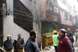 Policemen and neighbors stand in front of an ill-fated building which caught fire on Sunday, in New Delhi, India, Monday, Dec. 9, 2019. Authorities say an electrical short circuit appears to have caused a devastating fire that killed dozens of people in a crowded market area in central New Delhi. Firefighters fought the blaze from 100 yards away because it broke out in one of the area's many alleyways, tangled in electrical wire and too narrow for vehicles to access.