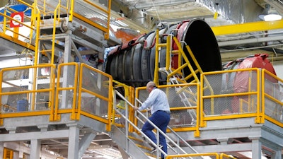 An employee walks up to two of the four rocket engines of NASA's Space Launch System (SLS) as the Artemis 1 rocket core stage is assembled at the NASA Michoud Assembly Center in New Orleans, Monday, Dec. 9, 2019.