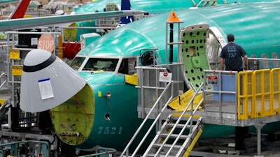 In this March 27, 2019, file photo, a worker enters a Boeing 737 MAX 8 airplane during a brief media tour of Boeing's 737 assembly facility in Renton, Wash. On Monday, Dec. 16, shares of Boeing are falling before the opening bell on a report that the company may cut production of its troubled 737 Max or even end production all together.