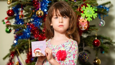 Florence Widdicombe, 6, poses with a Tesco Christmas card from the same pack as a card she found containing a message from a Chinese prisoner, in London, Sunday, Dec. 22, 2019. The U.K.-based grocery chain Tesco has halted production at a factory in China after a British newspaper said it used forced labor to produce charity Christmas cards. Tesco said Sunday it had stopped production and launched an investigation after the Sunday Times newspaper raised questions about the factory's labor practices.