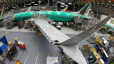 In this March 27, 2019, photo taken with a fish-eye lens, a Boeing 737 MAX 8 airplane sits on the assembly line during a brief media tour in Boeing's 737 assembly facility in Renton, Wash. The looming production shutdown of Boeing 737 Max jets is taking a toll on a key supplier. Spirit AeroSystems Holdings Inc. is asking employees if they will take voluntarily buyouts. Spirit suspended production of fuselages and other parts for the Max on Jan. 1, 2020, after Boeing told the Wichita, Kansas, company to suspend shipments.