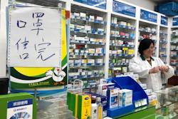 In this Tuesday, Jan. 21 file photo, pharmacist Liu Zhuzhen stands near a sign reading 'face masks are sold out' at her pharmacy in Shanghai, China. Panic and pollution drive the market for protective face masks, so business is booming in Asia, where fear of the virus from China is straining supplies and helping make mask-wearing the new normal.