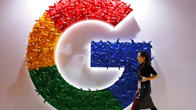 In this Monday, Nov. 5, 2018, file photo, a woman walks past the logo for Google at the China International Import Expo in Shanghai.