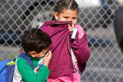 Children covering their noses and mouths leave school where multiple people were treated for jet fuel exposure at Park Avenue Elementary School in Cudahy, Calif., on Tuesday, Jan. 14, 2020. A jet returning to LAX dumped its fuel over the neighborhood and the school. Affected people at the school were treated for skin and eye irritation. No patients were transported to hospitals.