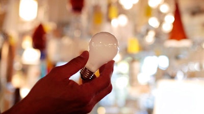 In this Jan. 21, 2011 file photo, manager Nick Reynoza holds a 100-watt incandescent light bulb at Royal Lighting in Los Angeles. A federal judge on Tuesday, Dec. 31, 2019, allowed California's updated light bulb efficiency standards to take effect with the new year Wednesday, Jan. 1, 2020. U.S. District Judge Kimberly Mueller of Sacramento rejected a petition from the National Electrical Manufacturers Association and the American Lighting Association to temporarily block new minimum efficiency standards for light bulbs that were adopted by the California Energy Commission in November.