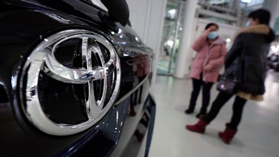 Visitors stand by a Toyota car displayed at its showroom Thursday, Jan. 30, 2020, in Tokyo. German automaker Volkswagen has kept its lead as the world's largest automaker as Japanese rival Toyota sold fewer vehicles last year. Toyota Motor Corp. said Thursday it sold 10.74 million vehicles around the world in 2019, trailing Volkswagen at 10.97 million vehicles.