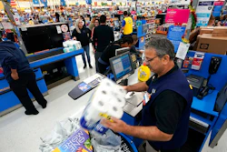 In this Nov. 9, 2018, file photo Walmart associate Javaid Vohar, right, checks out customers at a Walmart Supercenter in Houston. Walmart says it is testing higher wages for new hourly positions at 500 of its U.S. stores as part of an overall strategy to better empower its staff.