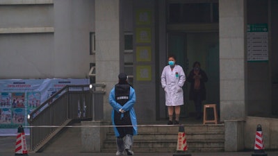 Hospital staff stand outside the emergency entrance of Wuhan Medical Treatment Center, where some infected with a new virus are being treated, in Wuhan, China, Wednesday, Jan. 22, 2020. The number of cases of a new coronavirus from Wuhan has risen to over 400 in China health authorities said Wednesday.