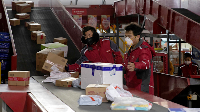 In this Tuesday, Feb. 18, 2020, photo, delivery workers for Chinese e-commerce giant JD.com sort out parcels at a distribution center in Beijing, China.