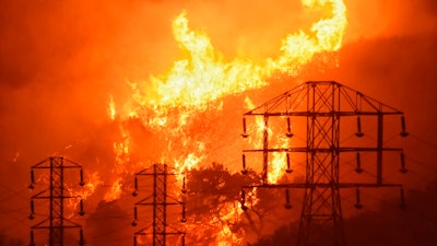 This Dec. 16, 2017 photo shows flames burning near power lines in Montecito, Calif.